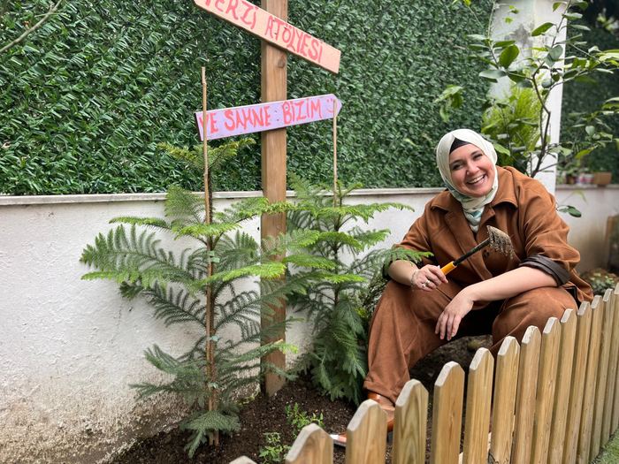 Sedef Demir, okul bahçesindeki el yapımı tabelanın yanında