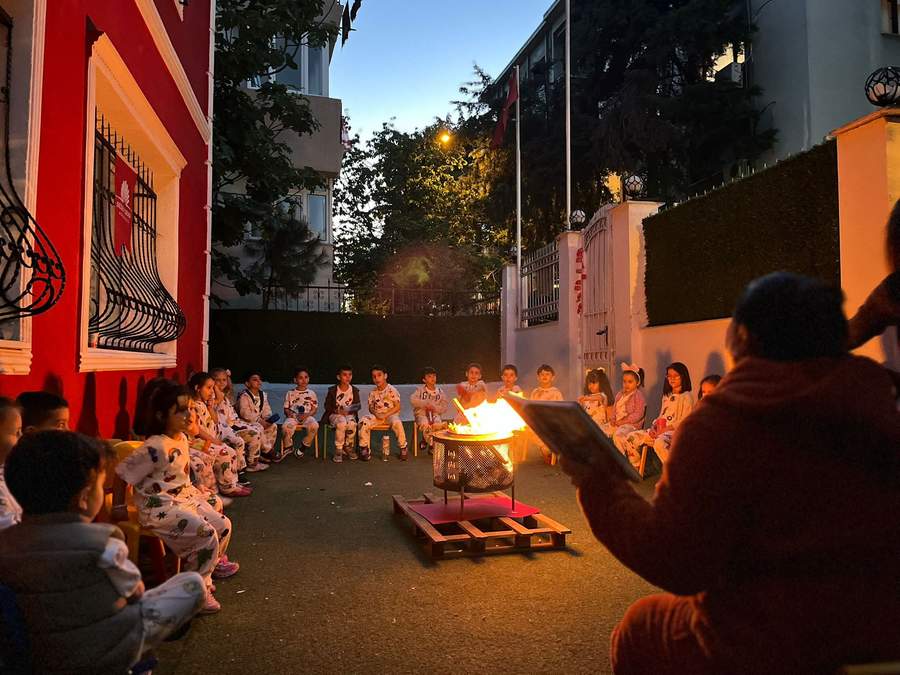 Pijama partisinde ateş başında hikaye dinleyen çocuklar