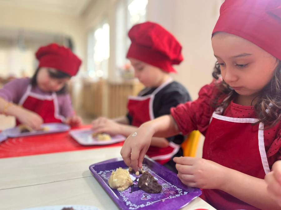 Mutfak atölyesinde kurabiye süsleyen çocuklar